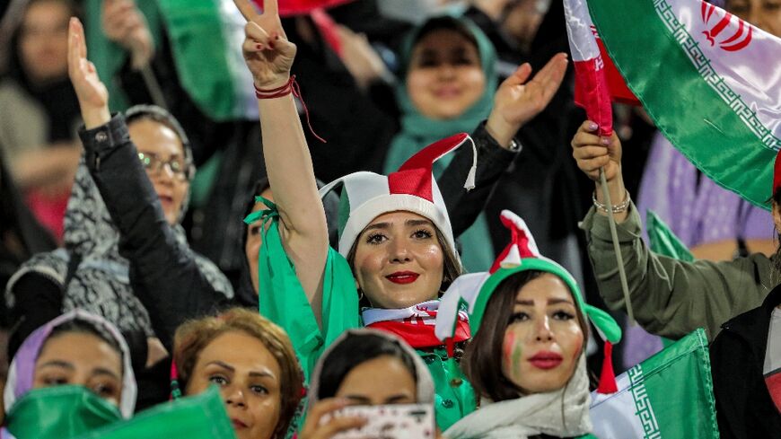 Women football fans wave national flags and cheer during a friendly match between Iran and Kenya in Tehran in March