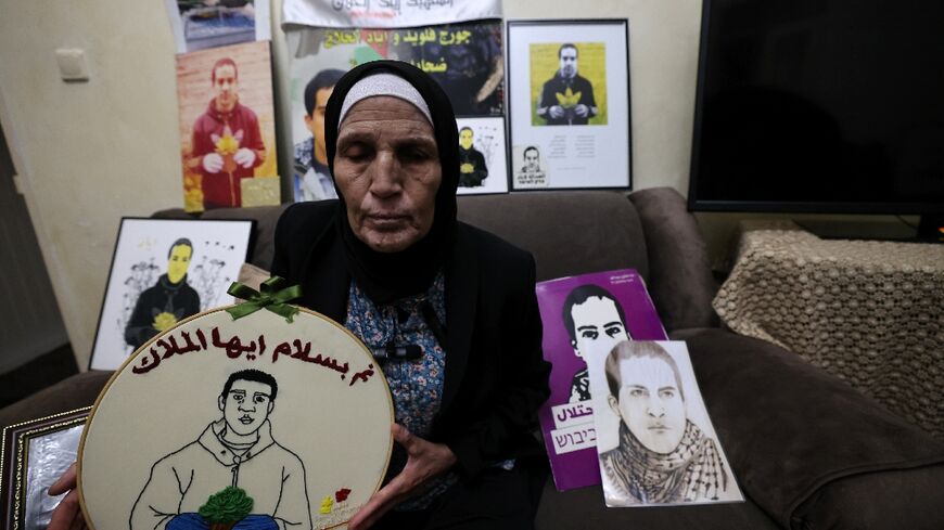The mother of Iyad Hallak, a Palestinian with autism shot dead in May 2020, sits surrounded by his portraits at her Jerusalem home