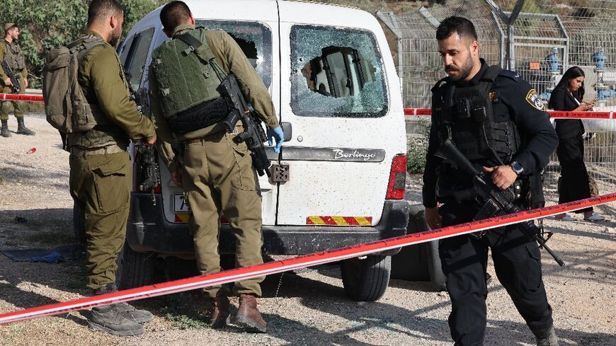 Israeli soldiers examine a damaged car following a reported attack in the occupied West Bank
