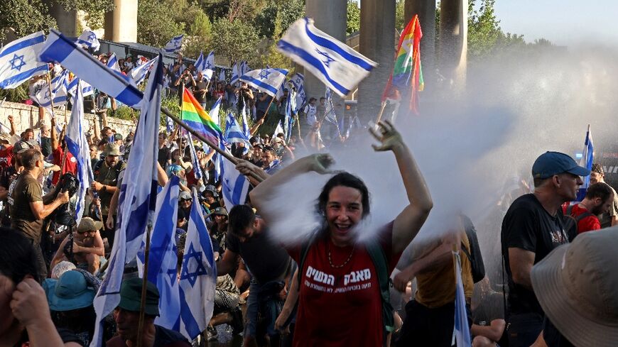 Israeli security forces use a water cannon to disperse demonstrators blocking the entrance to parliament