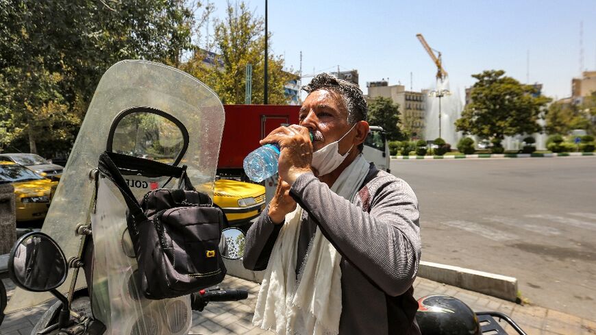 A motorcyclist takes a break in the heat of Tehran on July 11, 2023