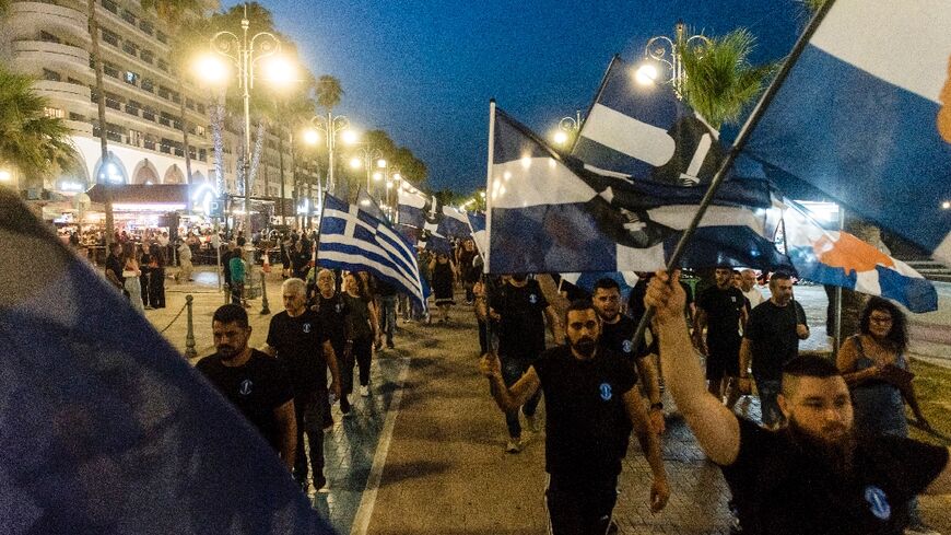 Supporters of Cyprus's far-right National Popular Front (ELAM) wave Greek and party flags as they protest in the resort city of Larnaca against the presence of migrants and asylum-seekers on the Mediterranean island