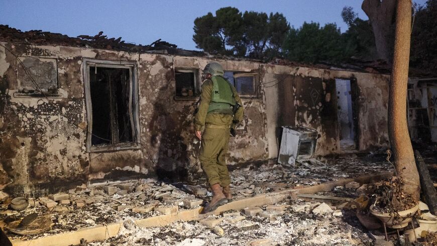 A member of Israel's security forces inspects a damaged building at kibbutz Beeri near the border with Gaza which was overrun by Hamas militants Saturday when they launched a shock surprise attack on Israel