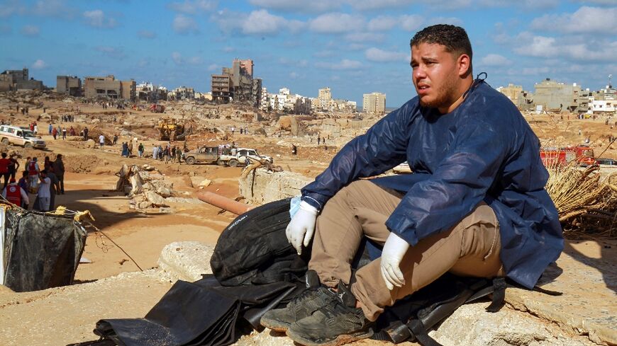 A volunteer sits on the rubble of a building in the aftermath of the flood disaster in Libya's Derna