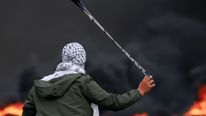A Palestinian hurls stones at Israeli forces during a demonstration against the Israli bombardment of the Gaza Strip, in the city of Ramallah in the occupied West Bank on October 11, 2023