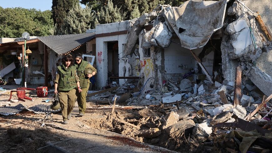 Israeli soldiers escort journalists on a tour of Kfar Aza, one of the kibbutz communities devastated by Hamas militants on October 7