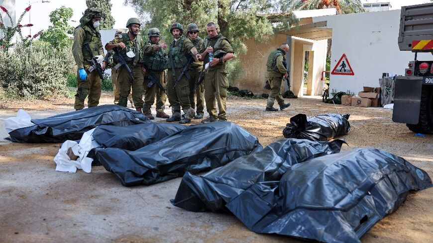 Israeli soldiers prepare to remove the bodies of compatriots killed by Palestinian militants in the kibbutz of Kfar Aza where more than 100 civilians are believed to have been massacred