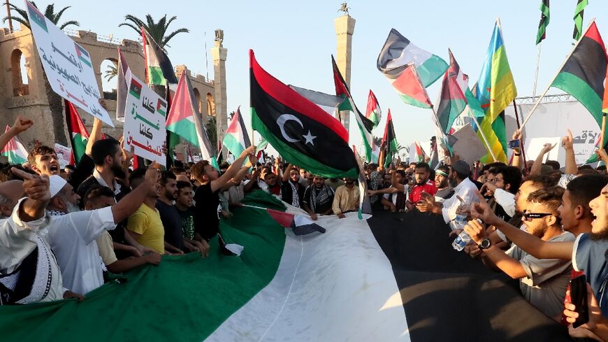 Libyans chant slogans and wave Palestinian and Libyan national flags as they march in solidarity with the people of Palestine 