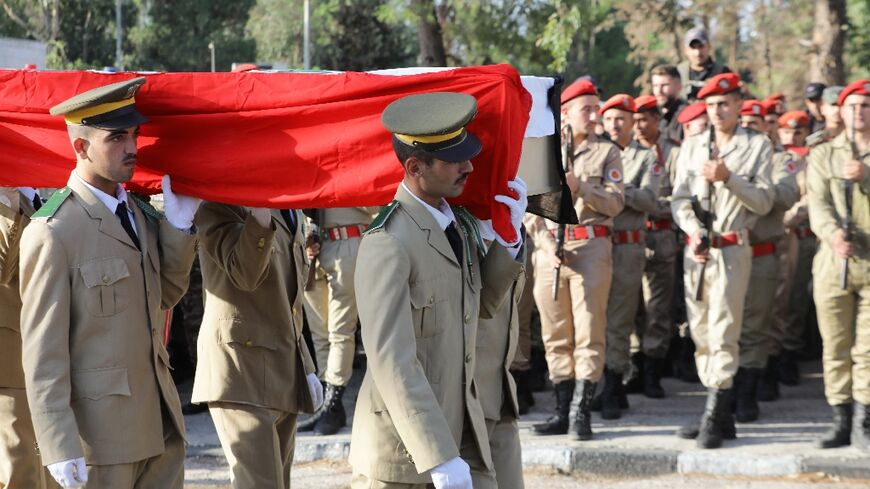 Soldiers carry a casket during the funeral of the victims of a drone attack on a Syrian military academy