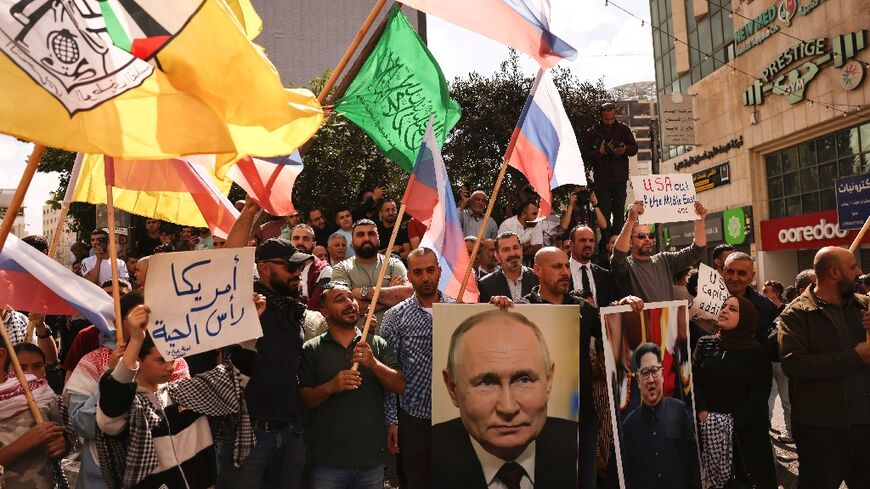 People wave Russian, Palestinian, Fatah and Hamas flags and carry portraits of Russia's President Vladimir Putin and North Koren leader Kim Jong Un on the streets of the occupied West Bank city of Hebron