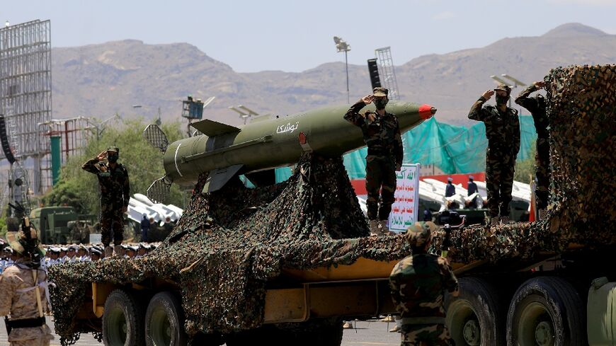 Huthi soldiers salute next to a missile during a parade in Sanaa in September