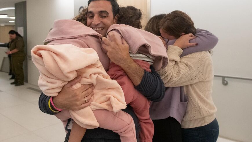 This handout picture released by the Israeli army, courtesy of the hostages' families, shows Yoni Asher welcoming his daughters and wife after they were released from Hamas captivity