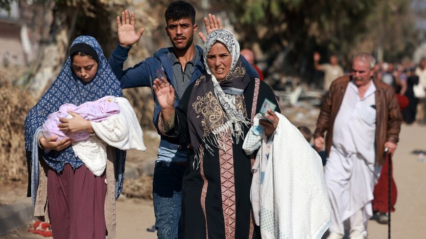 Palestinians fleeing heavy fighting northern Gaza raise their arms as they make the perilous journey south on foot