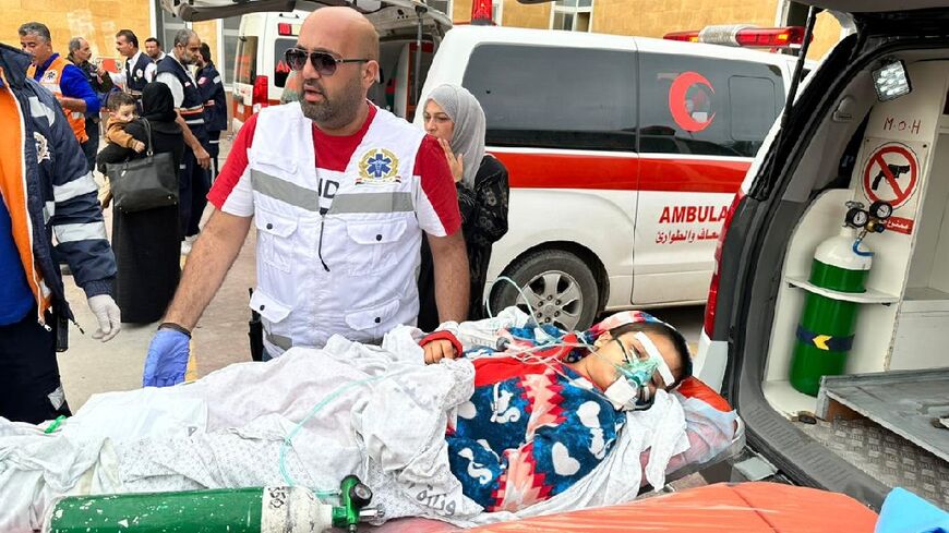Egyptian paramedics transport an injured Palestinian child to a Red Crescent ambulance upon her arrival from Gaza via the Rafah border crossing