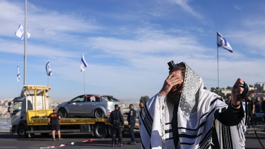 A religious Jew reacts at the scene of a fatal shooting in Jerusalem as a suspect vehicle is removed