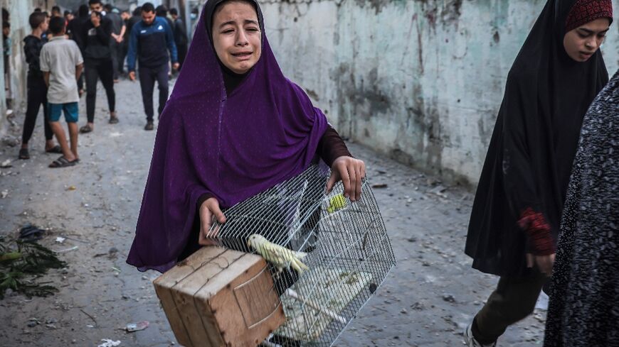 A girl carrying a bird cage flees following an Israeli strike in Rafah in the southern Gaza Strip 