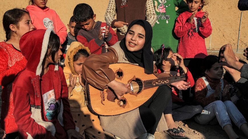 Volunteer entertainer Ruaa Hassouna plays her oud to Palestinian children in one of the makeshift camps that are now home to most of the Gaza Strip's 2.4 million people