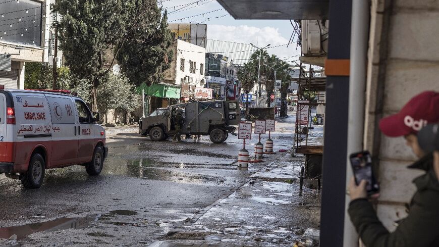 An Israeli army patrol car blocks off one of the entrance roads to Jenin refugee camp in the occupied West Bank as troops press a raid that has killed 11 Palestinians since Tuesday