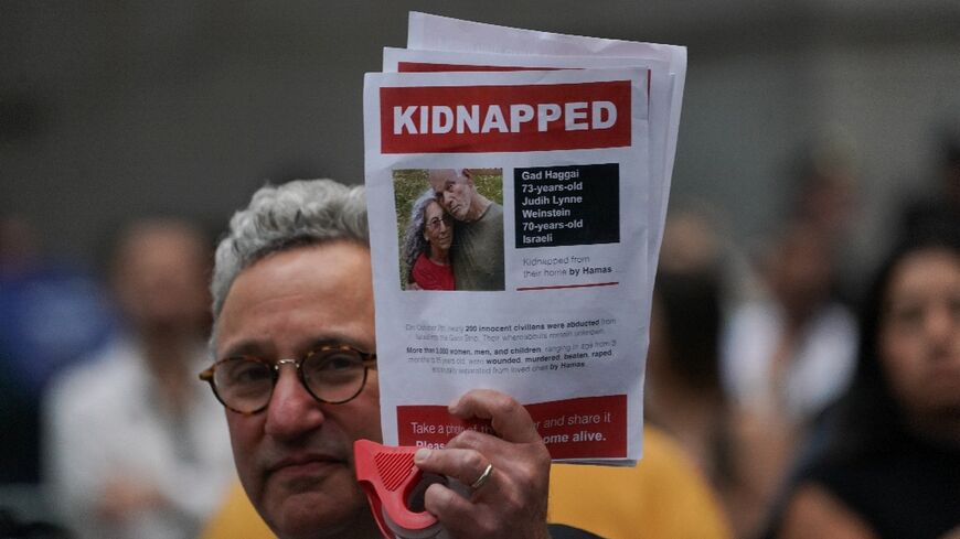 A man holds a picture of hostages Gad and Judith Weinstein Haggai -- both of whom have been confirmed killed -- during a New York rally on October 26, 2023 