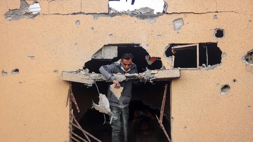 A man looks through the window of a damaged building in Rafah