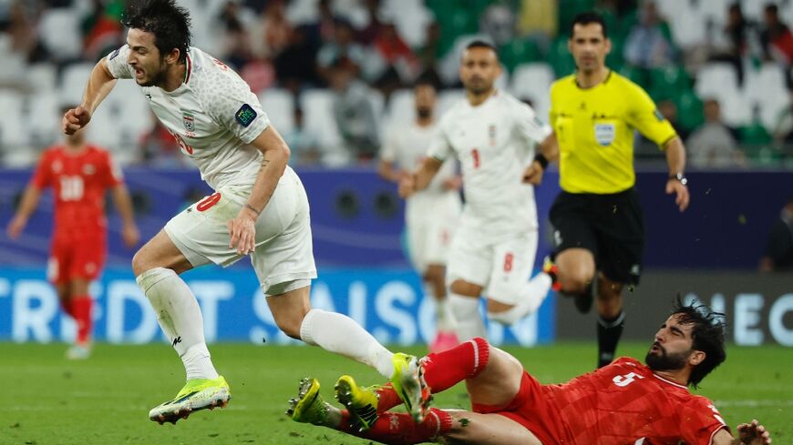 Palestine's defender #05 Mohammed Saleh tackles Iran's forward #20 Sardar Azmoun during the Qatar 2023 AFC Asian Cup Group C football match between Iran and Palestine