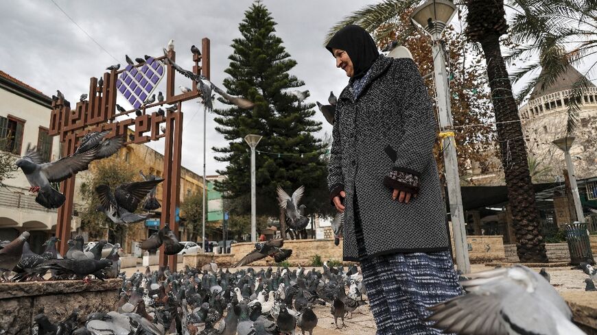 A woman stands among pigeons at the square outside the Roman Catholic Basilica of the Annunciation in Nazareth in northern Israel 