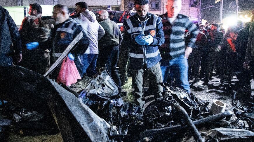 Rescuers check the wreckage of a car at the scene of a bomb explosion in the norther Syrian city of Azaz, early on March 31, 2024