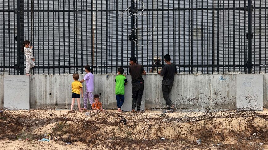 Displaced Palestinian children chat with an Egyptian soldier through the fence separating Egypt and Rafah in the southern Gaza Strip
