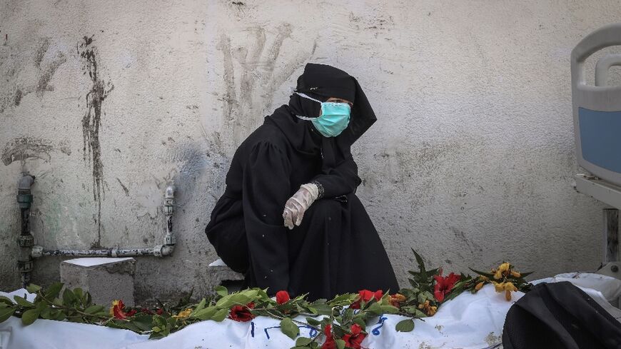 A woman mourns by a body unearthed at Nasser Hospital in Khan Yunis