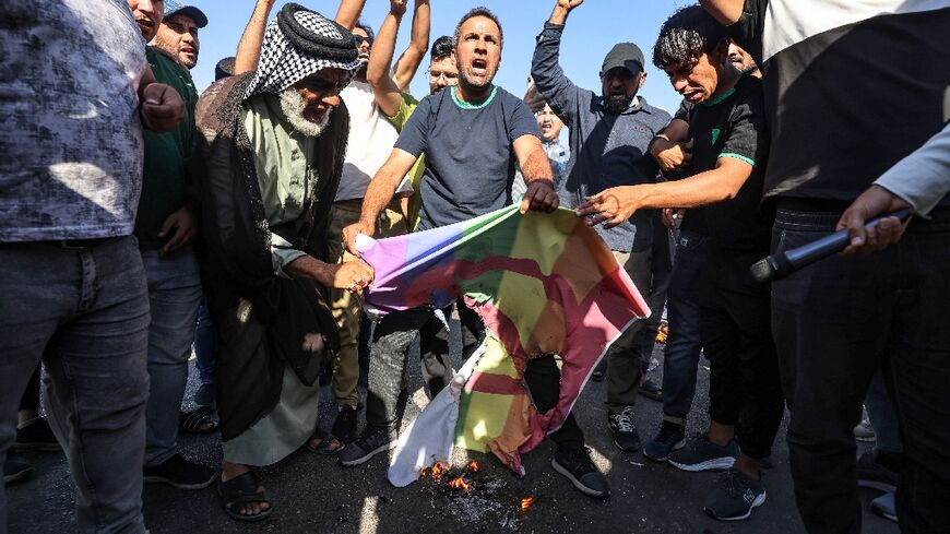 (FILES) Supporters of Shiite Muslim leader Moqtada Sadr burn a rainbow flag outside the Swedish embassy in Baghdad, after they breached the building over the burning of the Koran by an Iraqi living in Sweden