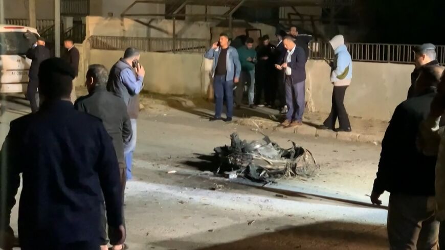 An image grab from AFPTV footage shows Jordanian onlookers and security agents standing around the debris of a missile that the Jordanian forces intercepted over Amman in the early hours of April 14, 2024
