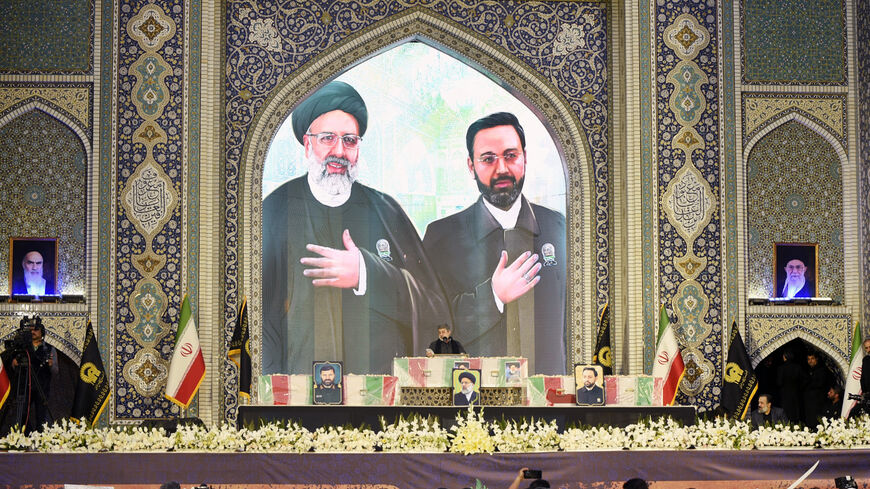 CORRECTION / An Iranian man reads a prayer over the coffins of late president Ebrahim Raisi (portrait top L) and late governor of Iran's East Azerbaijan Province Malik Rahmati (portrait top R) during a funeral ceremony at the Imam Reza shrine, in the city of Mashhad, on May 23, 2024. Raisi and seven members of his entourage, including foreign minister Hossein Amir-Abdollahian, were killed in a helicopter crash on a fog-shrouded mountainside in Iran on May 19. (Photo by Sadegh NIKGOSTAR / FARS NEWS AGENCY / 