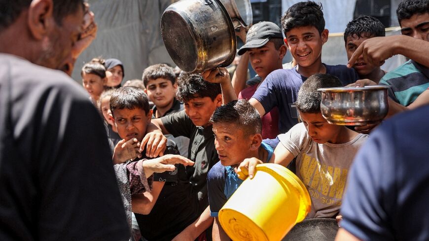 Children queue in Jabalia refugee camp to receive food aid from a kitchen at the Abu Zeitun school run by UNRWA, the UN agency for Palestinian refugees