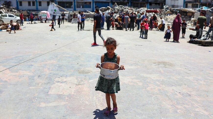 A child carries food at a UN agency for Palestinian refugees (UNRWA) school in Jabalia camp, northern Gaza, where the UN has warned of famine