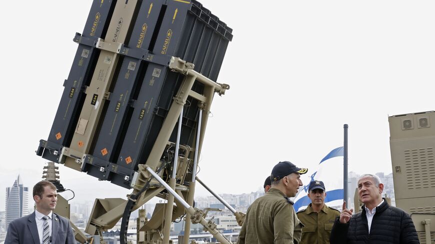 A picture taken on February 12, 2019, shows Israeli Prime Minister Benjamin Netanyahu (R) discussing with soldiers as he stands near a naval Iron Dome defence system, designed to intercept and destroy incoming short-range rockets and artillery shells, installed on a Sa'ar 5 Lahav Class corvette of the Israeli Navy fleet, in the northern port of Haifa. (Photo by JACK GUEZ / POOL / AFP) (Photo credit should read JACK GUEZ/AFP via Getty Images)