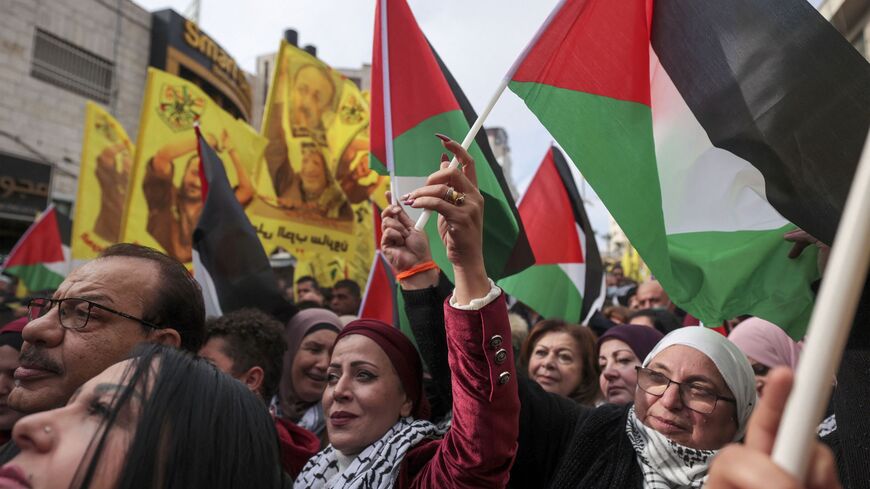 Palestinians wave their national flags, and banners bearing the image of jailed Fatah leader Marwan Barghuti with a slogan demanding his release and referring to him as the "symbol of freedom", during a celebration marking the 57th anniversary of Fatah movement's foundation, in Ramallah, in the Israeli-occupied West Bank, on December 30, 2021.