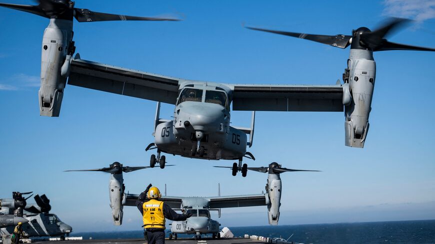 An Aviation Boatswains Mate (Bottom) signals to the pilots of an MV-22 Osprey assault support aircraft, assigned to the 22nd Marine Expeditionary Unit, as it departs off the flight deck of the Wasp-class amphibious assault ship USS Kearsarge (LHD 3), Baltic Sea, June 7, 2022.
