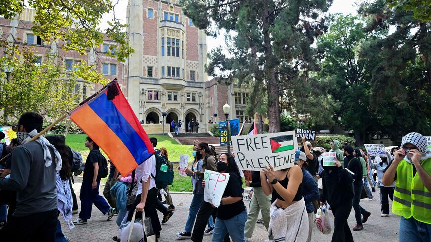 A protester holds an Armenian national flag next to a placard with a Palestinian flag as students participate in a "Walkout to fight Genocide and Free Palestine" at Bruin Plaza at UCLA (University of California, Los Angeles) in Los Angeles on October 25, 2023. Thousands of people, both Israeli and Palestinians have died since October 7, 2023, after Palestinian Hamas militants based in the Gaza Strip, entered southern Israel in a surprise attack leading Israel to declare war on Hamas in Gaza the following da