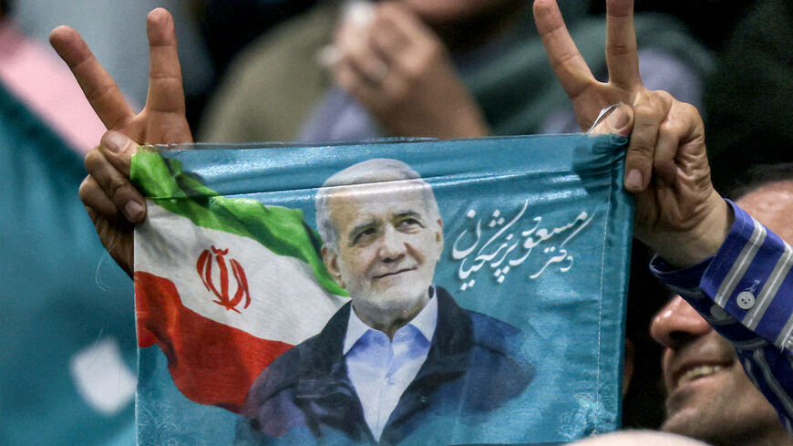 A man gestures as he holds up a small election flag during a campaign rally for reformist candidate Massoud Pezeshkian at Afrasiabi Stadium in Tehran on June 23, 2024 ahead of the upcoming Iranian presidential election. (Photo by ATTA KENARE / AFP) (Photo by ATTA KENARE/AFP via Getty Images)