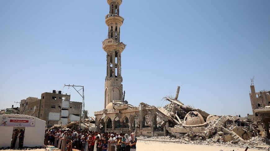 Muslims perform the Friday noon prayer in front of a destroyed mosque in Khan Yunis in the southern Gaza Strip, ahead of Eid al-Adha
