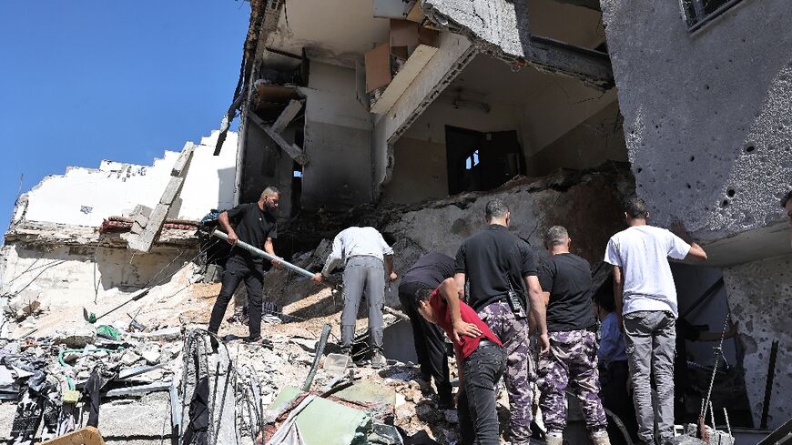 People search the rubble of a building hit by bombardment at the Nur Shams refguee camp in the occupied West Bank