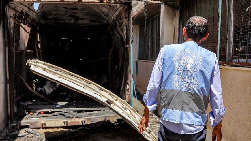 A UN worker inspects the remains of a container hit by Israeli bombardment at a school in Gaza's Al-Shati refugee camp
