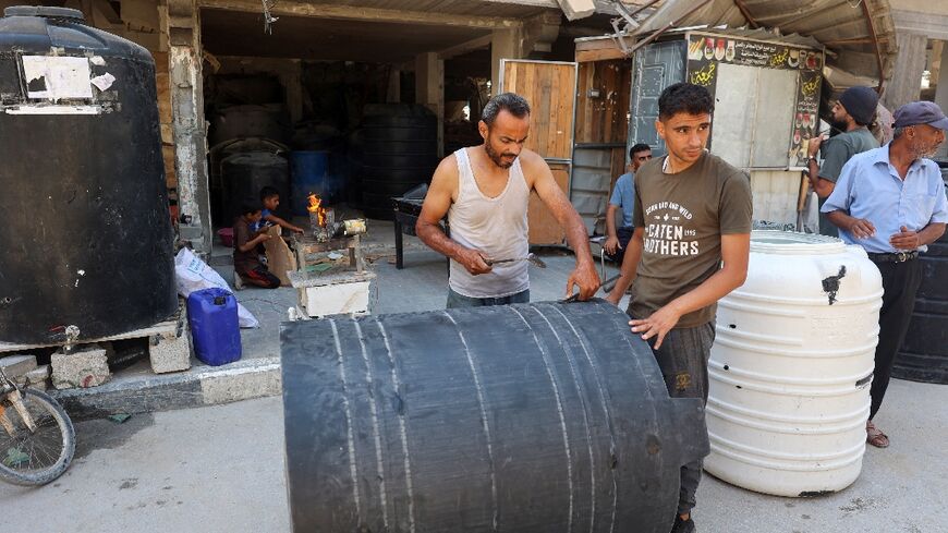 A man repairs water tanks damaged during Israeli bombardment in the southern Gaza Strip 