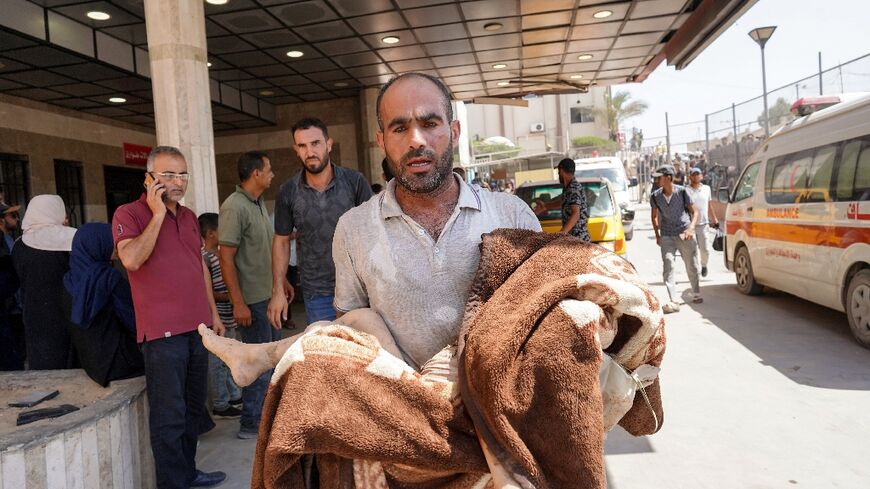A man carries a child wrapped in a blanket at the Nasser hospital after Israeli strikes in the Khan Yunis area