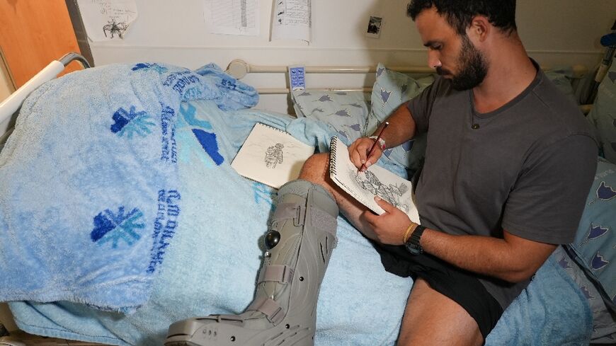 Barak, whose leg was shredded by a grenade during a hostage rescue mission in Gaza, draws as he sits on his bed at the Ichilov hospital in Tel Aviv