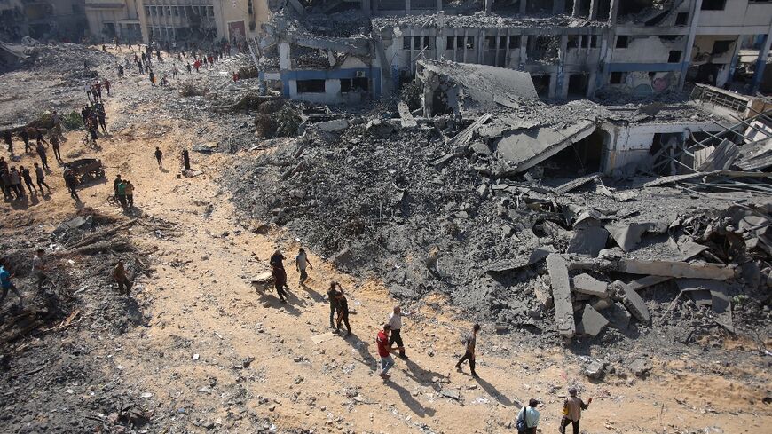 Palestinian civilians walk past the ruins of bombed out buildings in Gaza City's Al-Sinaa neighbourhood after Israeli troops back