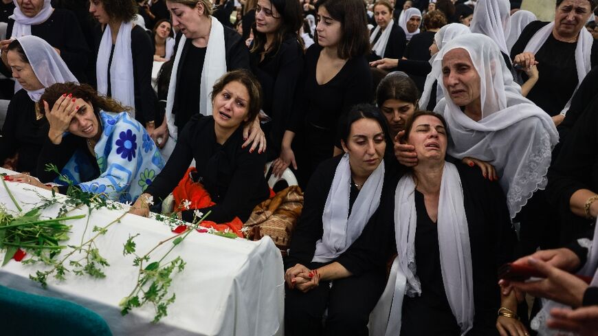 Druze women mourn by a coffin during a funeral after a rocket strike from Lebanon which, Israel's military said, killed 12 young people