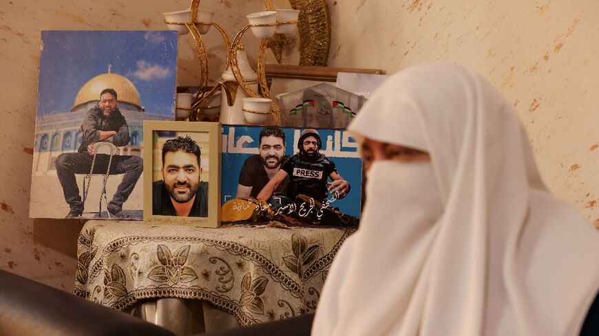 Palestinian journalist Moath Amarneh's mother Fatima next to his portraits at home in the West Bank's Dheisheh camp