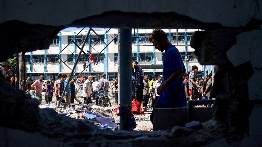 Palestinians check the destruction at the UN-run Al-Razi School in the Nuseirat refugee camp after an Israeli strike