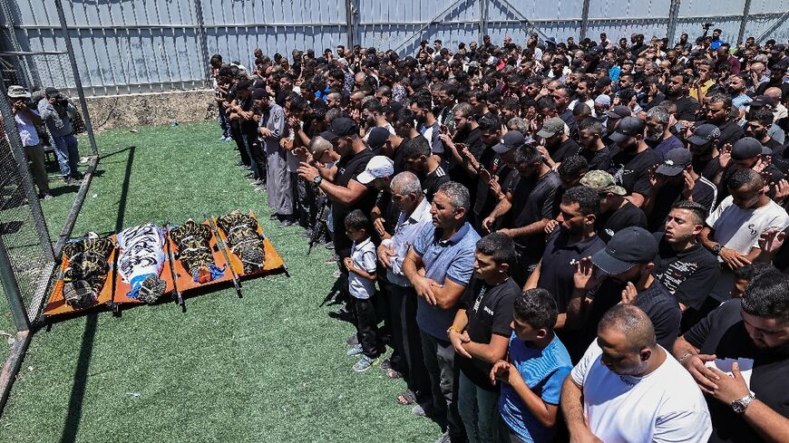 Mourners and gunmen at the funeral of four Palestinian militants killed in an Israeli airstrike on a refugee camp in the occupied West Bank